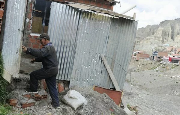 Lucas Morales entra en su casa a orillas del río Irpavi, en La Paz. [Jorge Bernal/AFP]