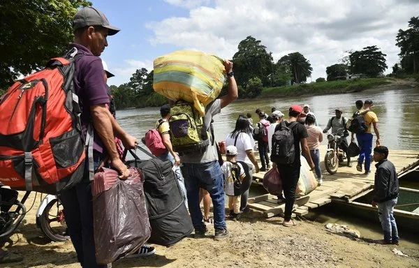 Displaced individuals from recent armed clashes board canoes to cross the Tarra River, a natural border between Colombia and Venezuela, in Tibu, Colombia. [Schneyder Mendoza/AFP]