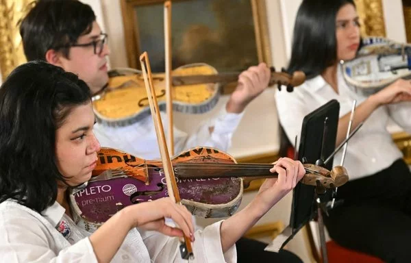 Integrantes de la Orquesta Paraguaya de Reciclados Cateura ensayan antes de una actuación en Lancaster House, en Londres. [Justin Tallis/AFP]