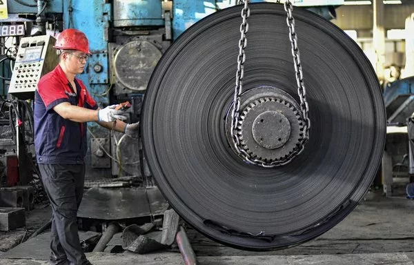 Un empleado trabaja en una fábrica que produce materiales de acero inoxidable en Qingzhou, China. [AFP]