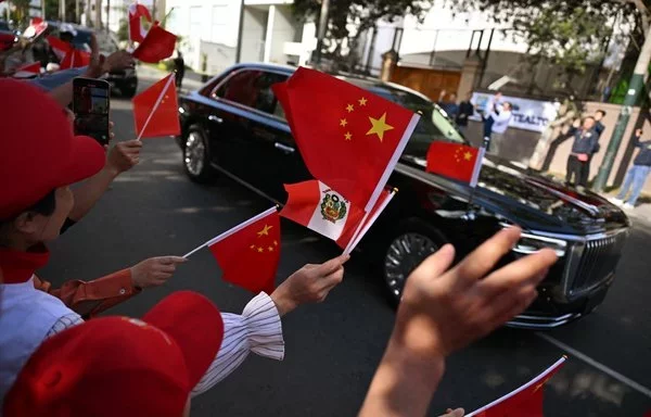 
Ciudadanos chinos en Perú ondean banderas mientras el automóvil que transporta al presidente Xi Jinping pasa por el hotel Los Delfines, donde trató sobre varios temas con el presidente chileno Gabriel Boric durante la Cumbre de la APEC en Lima el pasado noviembre. [Ernesto Benavides/AFP]        