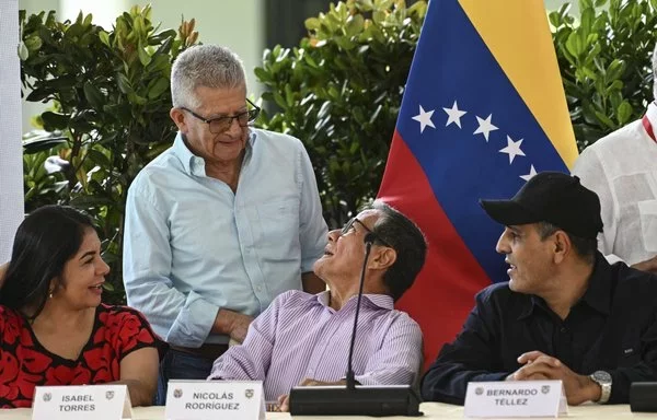 (De izquierda a derecha) Los delegados del Ejército de Liberación Nacional (ELN) Isabel Torres, Aureliano Carbonell, Nicolás Rodríguez y Bernardo Téllez conversan durante un evento relacionado con las conversaciones de paz con el gobierno colombiano en Caracas en septiembre de 2023. Al fondo se ve una bandera venezolana. [Yuri Cortez/AFP]