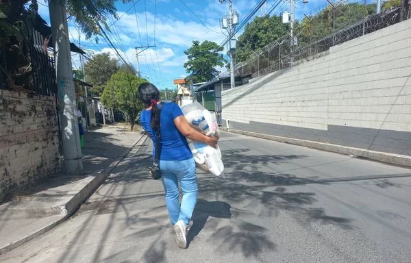 Una mujer lleva alimentos y ropa al Centro Penitenciario de Quezaltepeque, en El Salvador, para un familiar encarcelado. A las familias de los detenidos se les permite llevar un paquete mensual con alimentos no perecederos, ropa blanca nueva, kits de higiene y medicamentos esenciales. [Gaby Chávez]