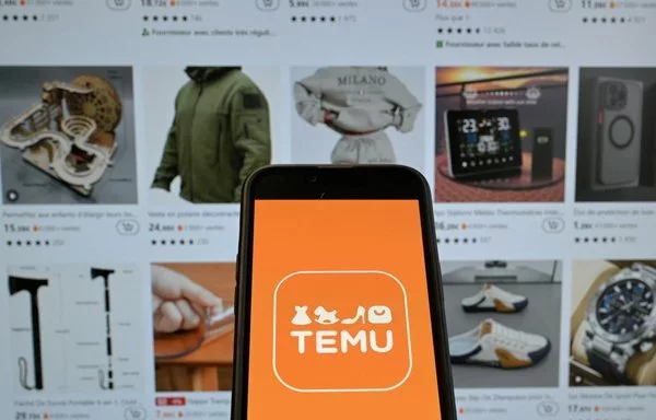 En esta imagen, el logotipo de la empresa china de venta online Temu aparece en un teléfono móvil delante del sitio web de la empresa. [Nicolas Tucat/AFP]