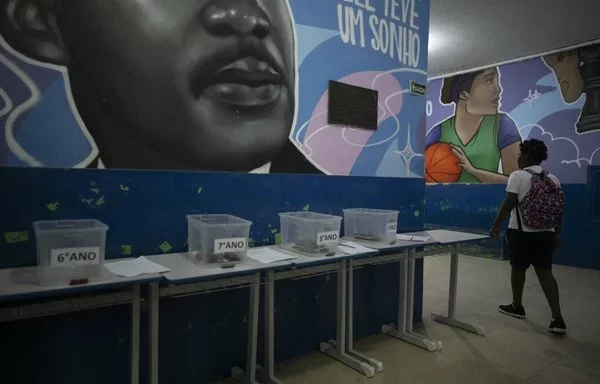 Estudiante de la escuela pública Reverendo Martin Luther King coloca su celular en una caja asignada antes de dirigirse a clase en Río de Janeiro, Brasil. [Pablo Porciuncula/AFP]