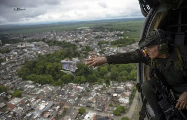 La policía antinarcóticos colombiana distribuye panfletos desde un helicóptero sobre Apartadó, Antioquia, ofreciendo recompensas por información que facilite la captura de miembros del cártel del Clan del Golfo. [Raúl Arboleda/AFP]