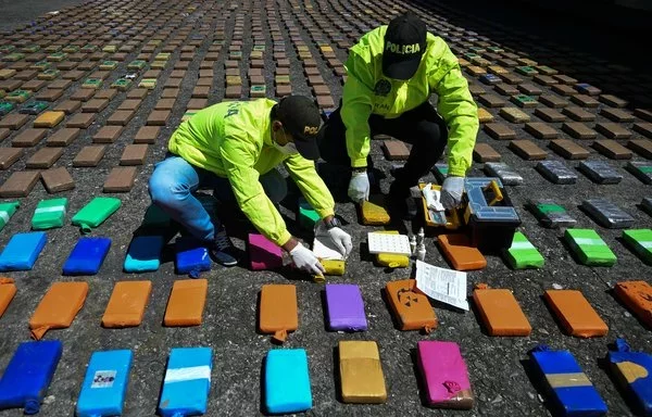 La policía antidrogas colombiana ordena los paquetes de un cargamento de una tonelada de cocaína incautado al cártel del Clan del Golfo en Buenaventura, el principal puerto colombiano del Pacífico. La mercancía iba destinada a Europa. [Raúl Arboleda/AFP]